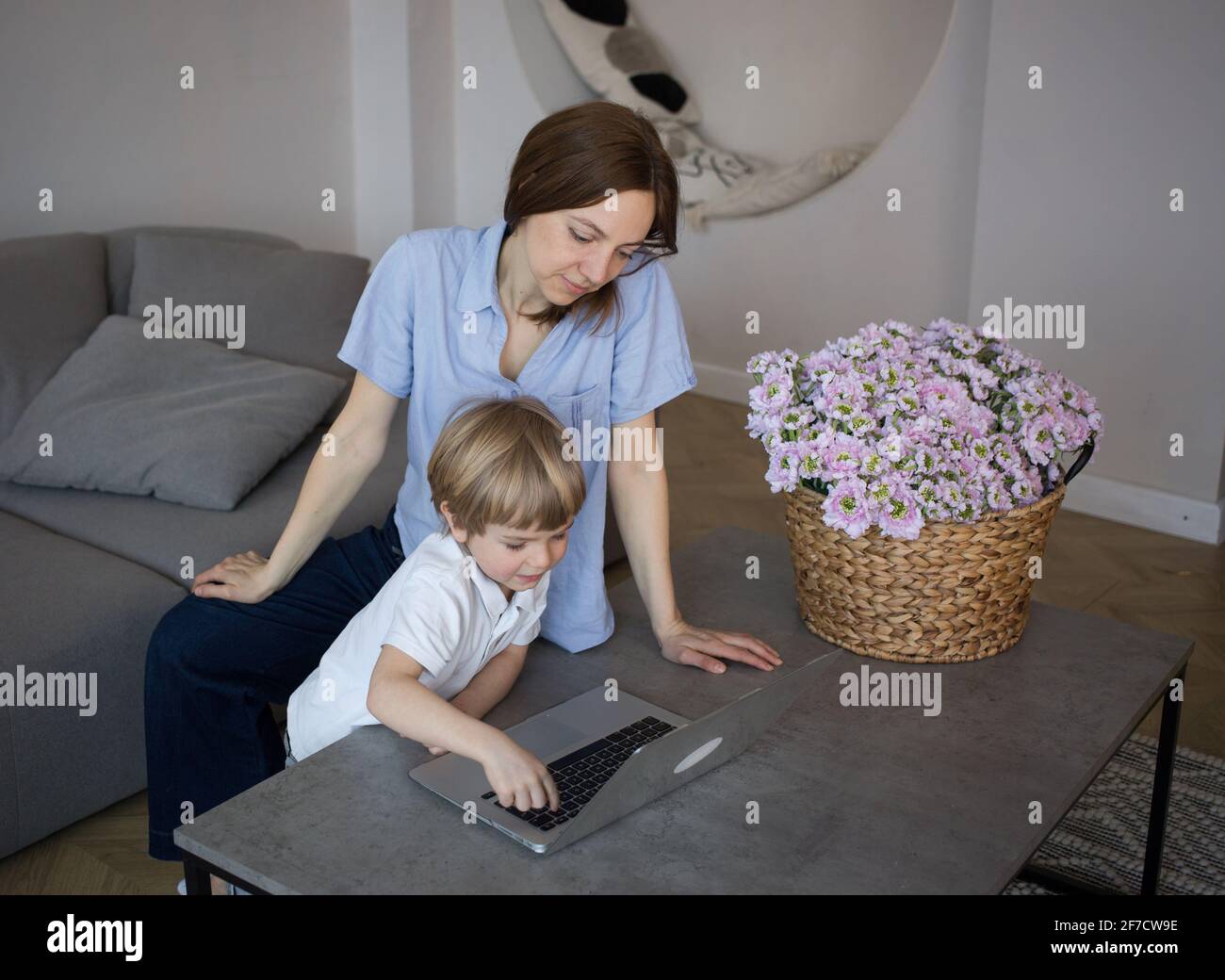 mom and son are looking at a laptop, online distance learning, helping ...