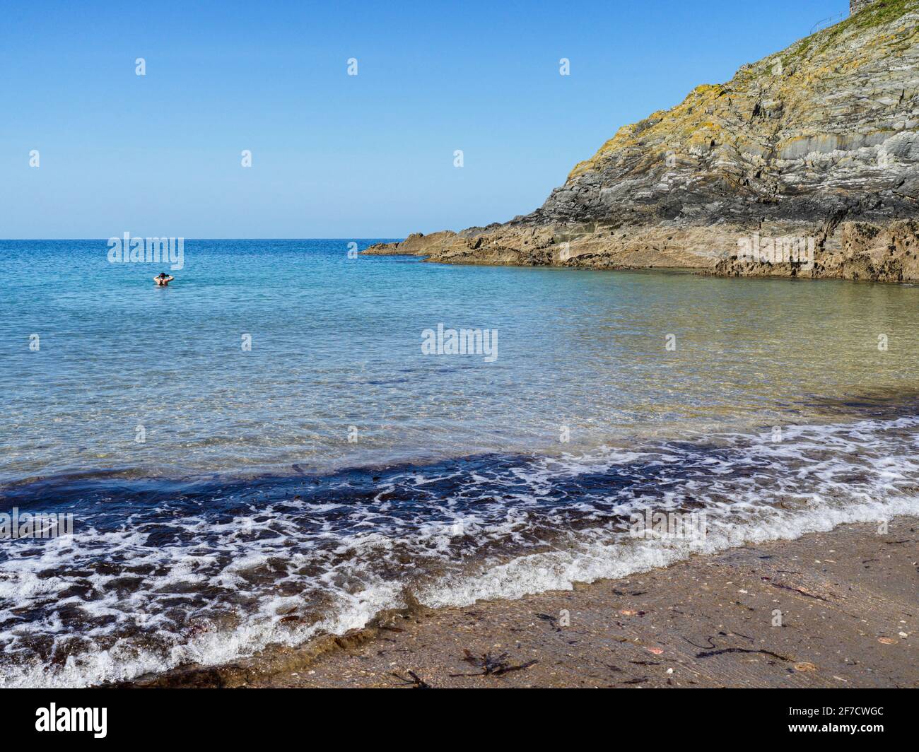 A lone woman swimmer at the sheltered Fenella Beach below Peel castle in the Isle of Man Stock Photo