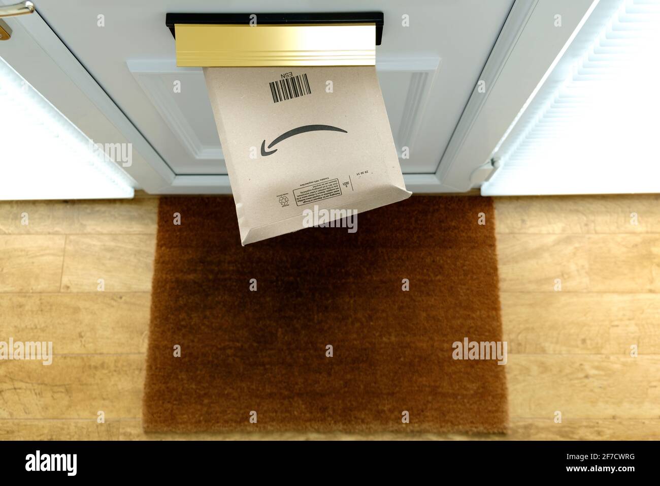 An Amazon Prime parcel delivery pushed through a house letter box in a house front door. The package is still in the letter box  and viewed from above Stock Photo