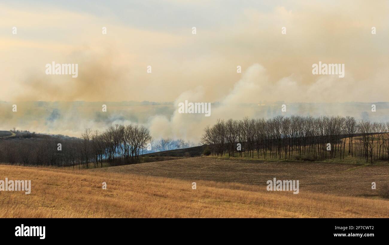 Thick clouds of smoke billow up from blazing grassland during a ...