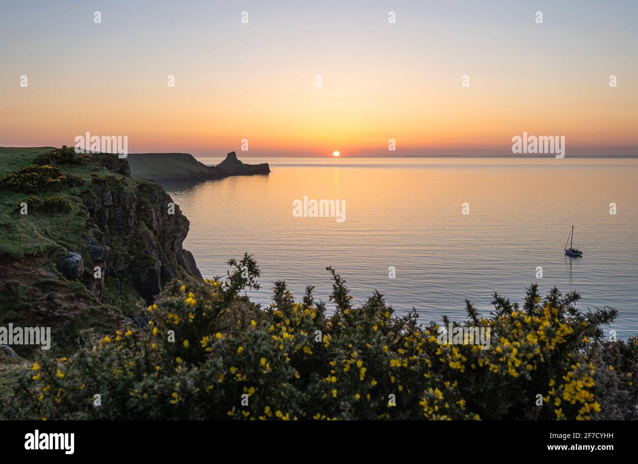 Worm's head Rhossili Bay at sunset and a single boat, Gower peninsula, South Wales, UK Stock Photo