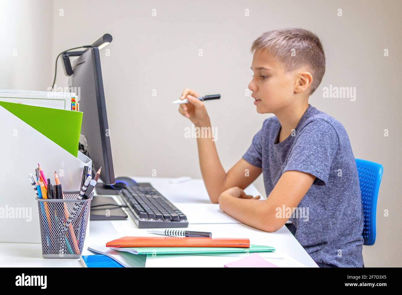 Online learning, remote education at home. Teenage boy with comouter has video call, makes homework at home Stock Photo