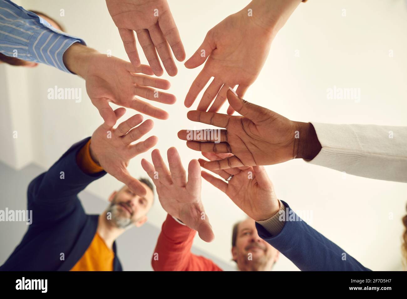 Shot from below of group of business people joining hands showing unity and team spirit Stock Photo