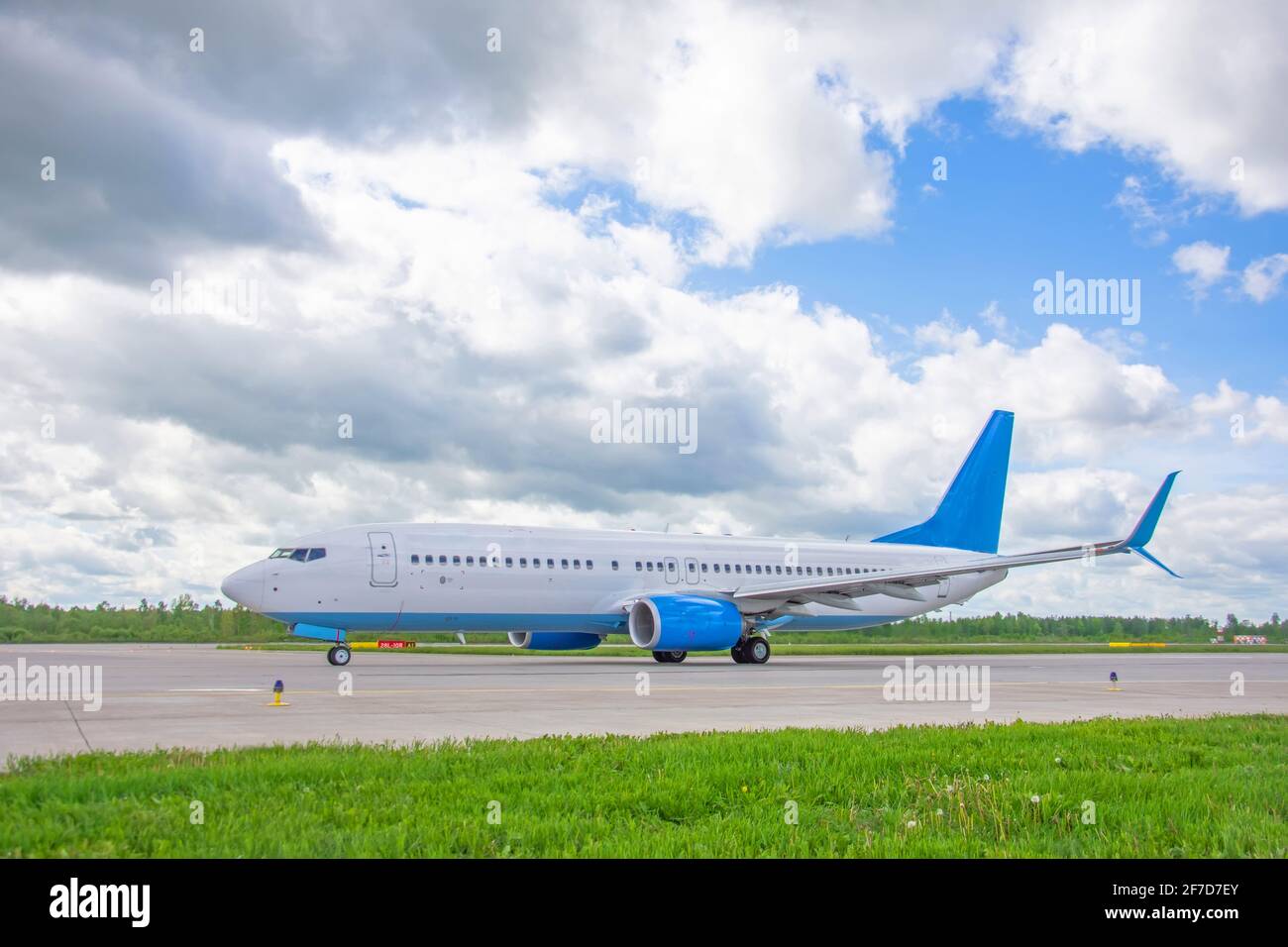 Airplane on airport taxiway bright green grass and scenic blue sky with clouds Stock Photo