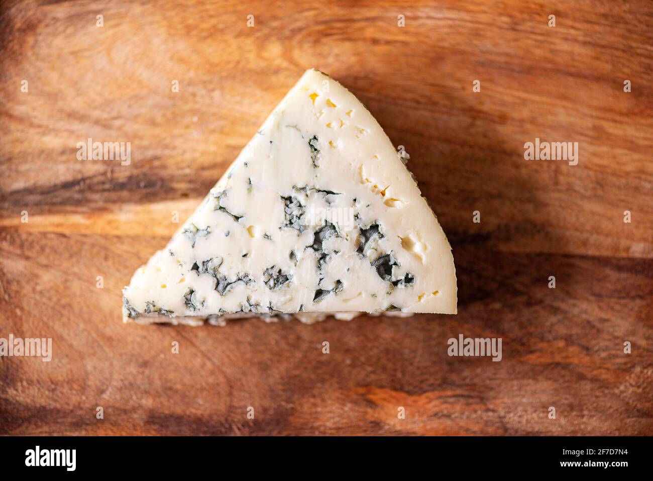 A piece of blue cheese, cheese with mold on wooden texture. French