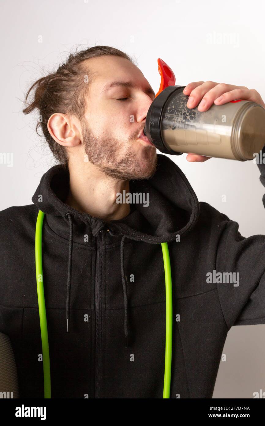 A Young Bearded Man Drinking A Protein Shake After Working Out a-young-bearded-man-drinking-a-protein-shake-after-working-out