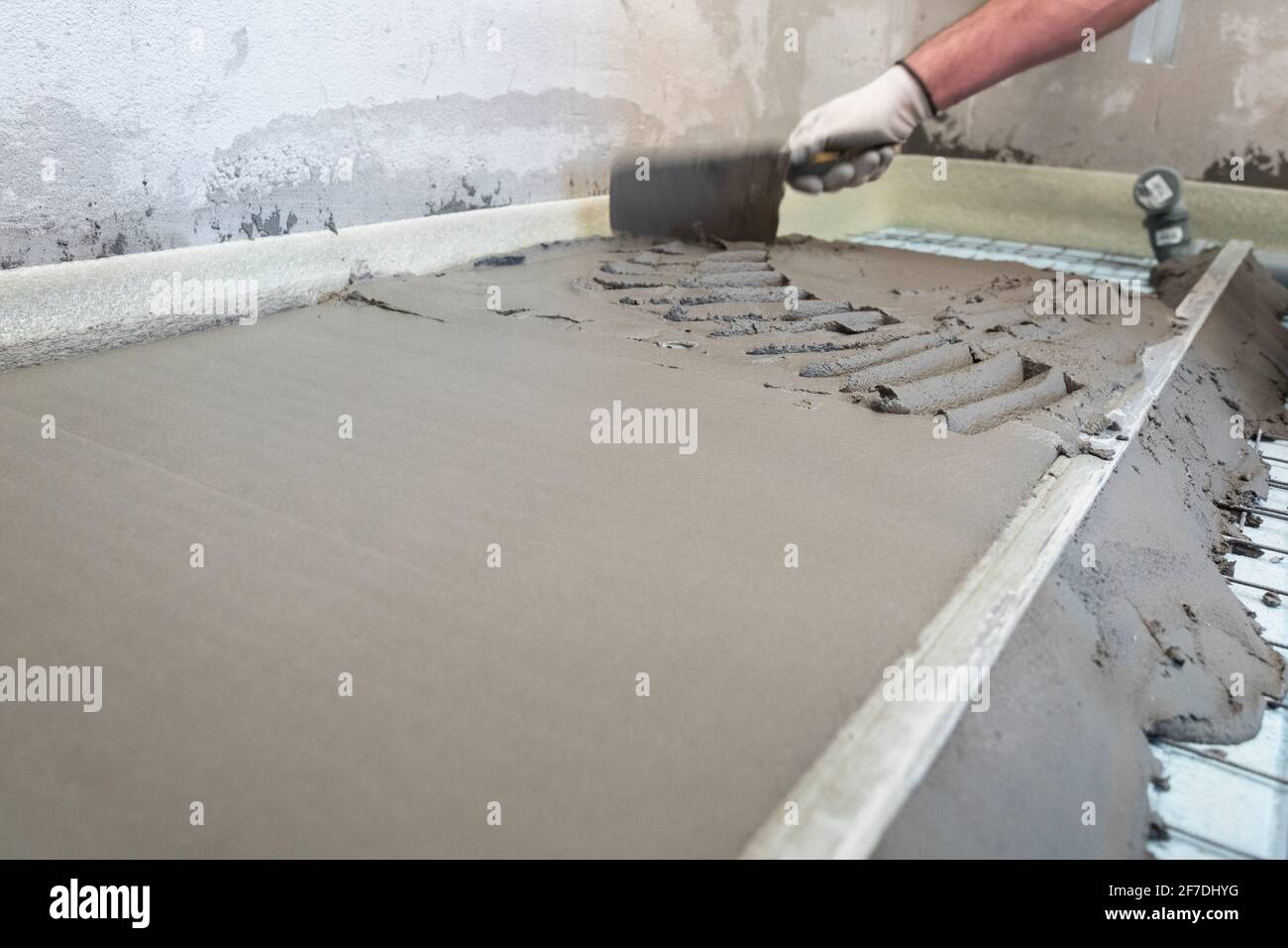 Construction worker performs floor screed indoors. Leveling the floor ...