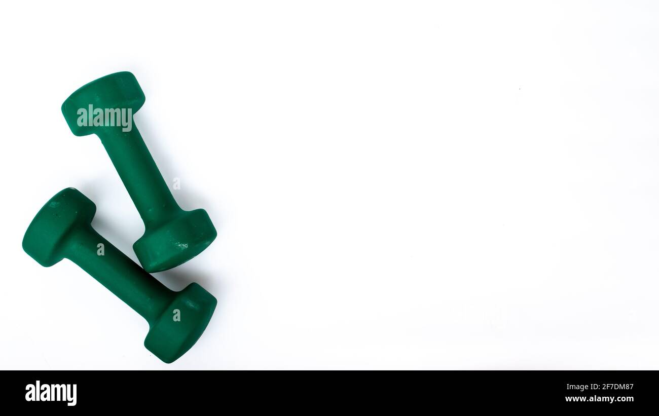 A pair of green dumbbells on a white background, isolated, lots of space for copy or text. Stock Photo