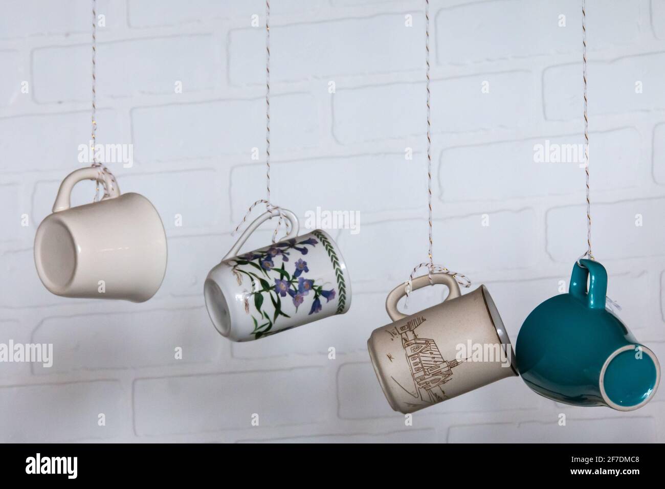 Coffee or tea ceramic mugs dangling from strings at a cute retro cafe in the wintertime. Stock Photo