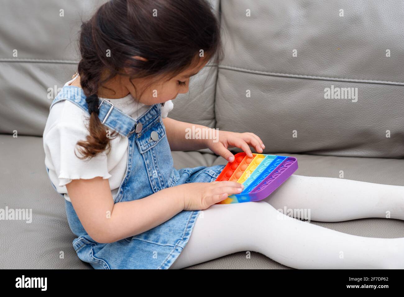 Sitting Fidget Young Little Girl Sitting On The Sofa At Home Playing Poppit-New Fidget ...
