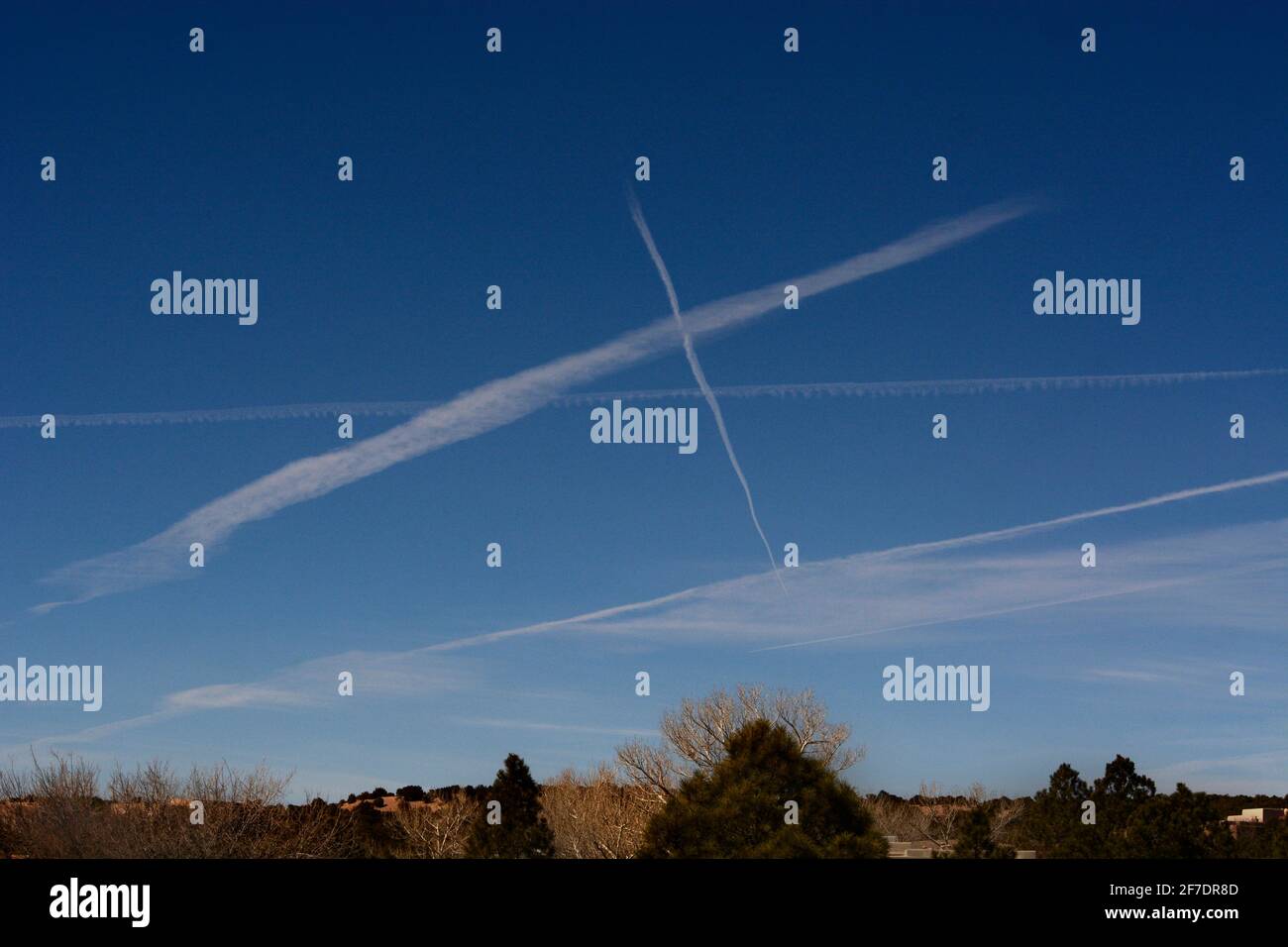 Jet aircraft leave streaks of contrails as they fly high over the