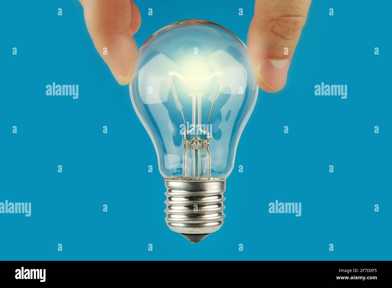 Hand holding glowing a light bulb with blue background. Concept and idea background. Bright idea. The way to solve problem. Stock Photo