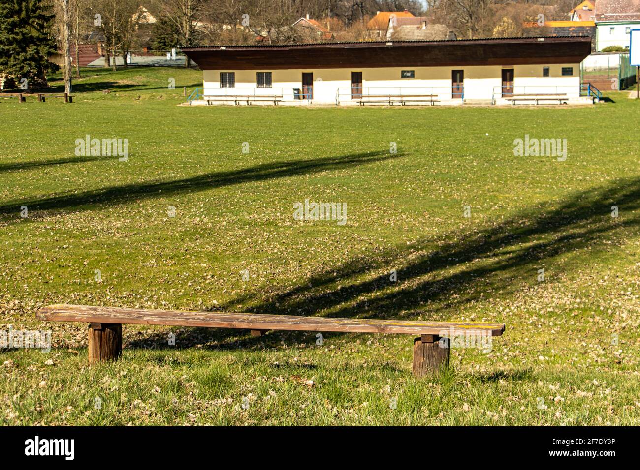 The empty wooden bench at the provincial football playground with dressing room for player. Stock Photo