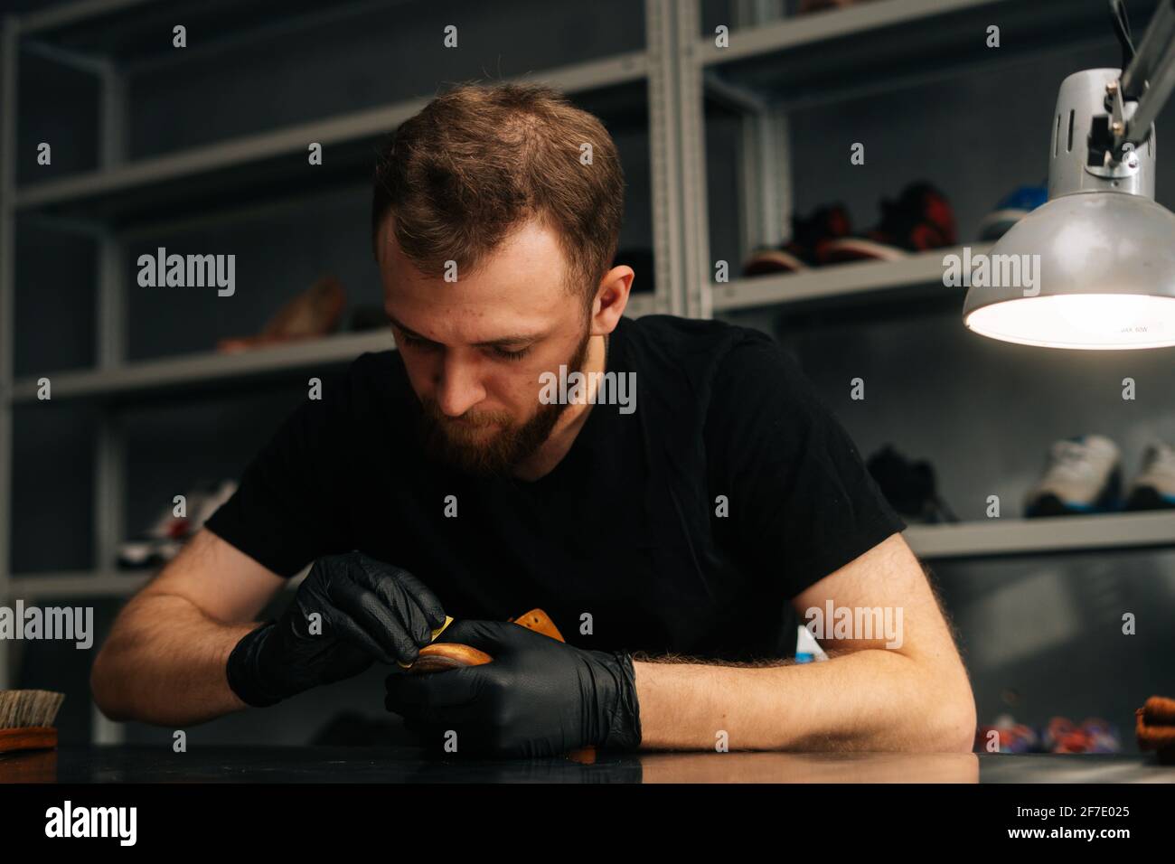 Front view of shoemaker wearing black latex gloves polishing old light