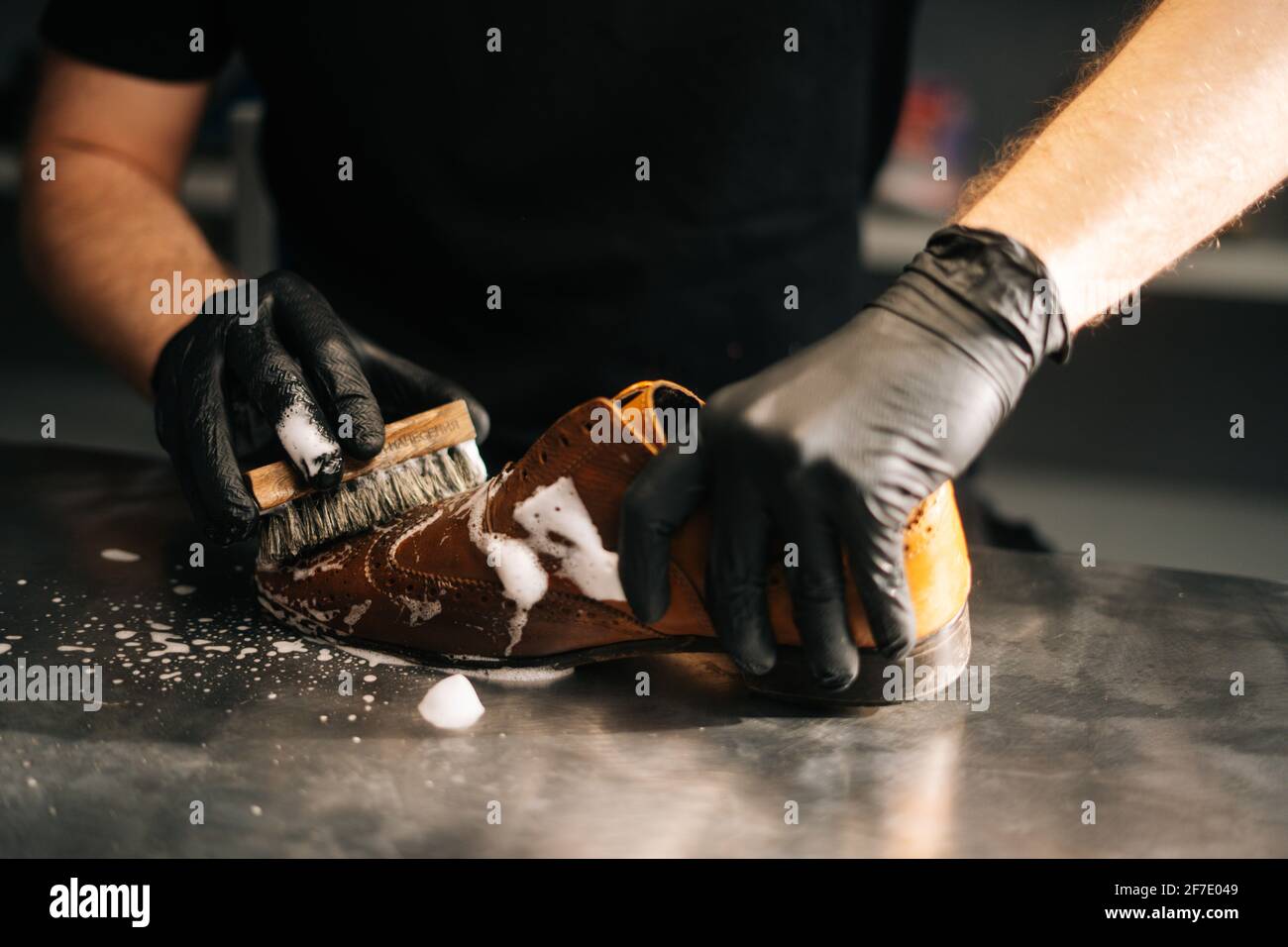 Close up hands of unrecognizable shoemaker in black gloves