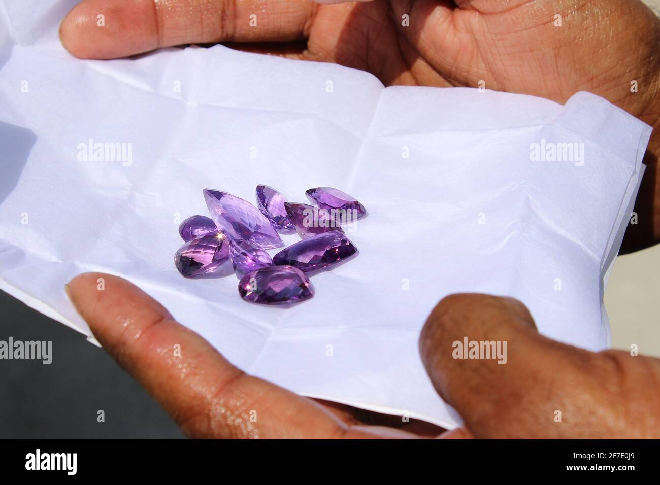Men hands with purple gem stones on piece of white paper Stock Photo