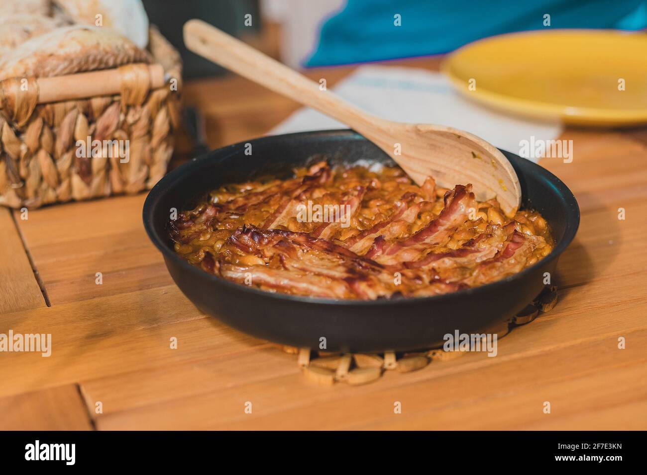 A black bowl of traditional food made of beans prebranac with slices of bacon served at a picnic. Stock Photo