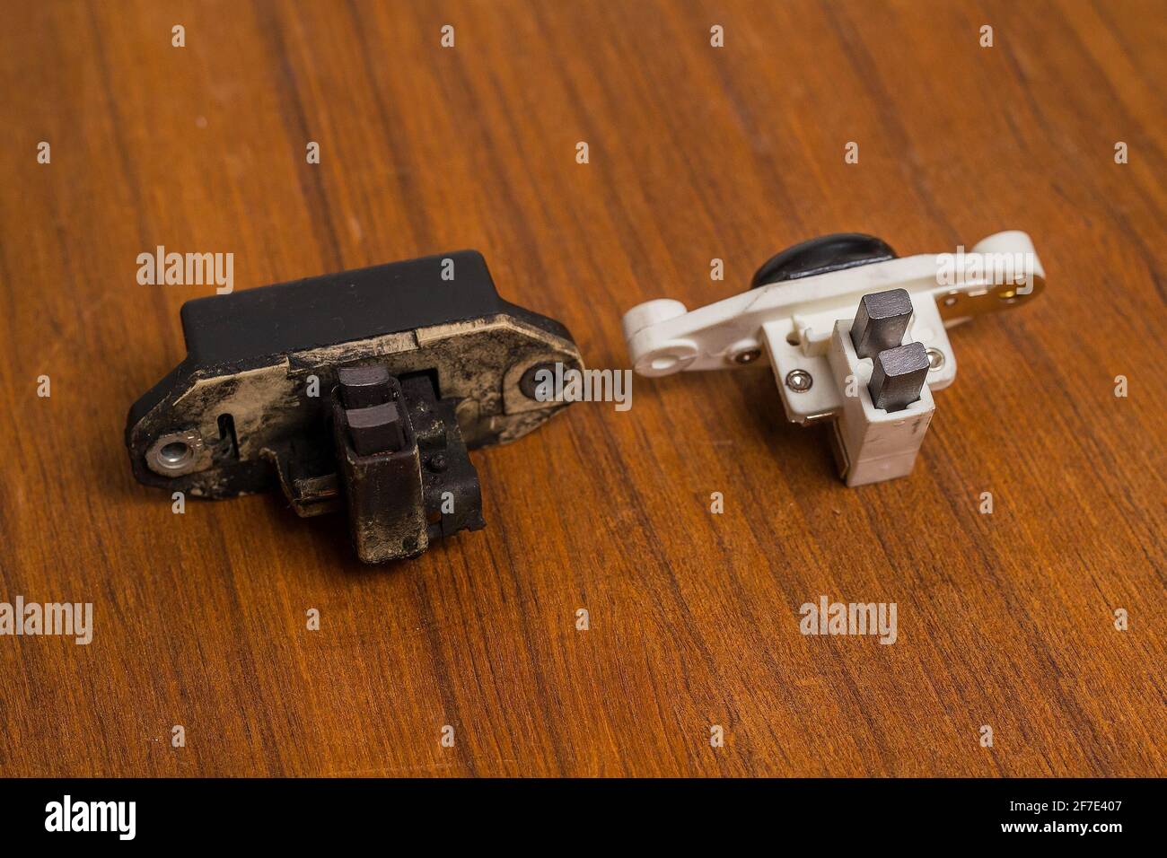 Comparison of old and new alternator brushes and regulator on a wooden