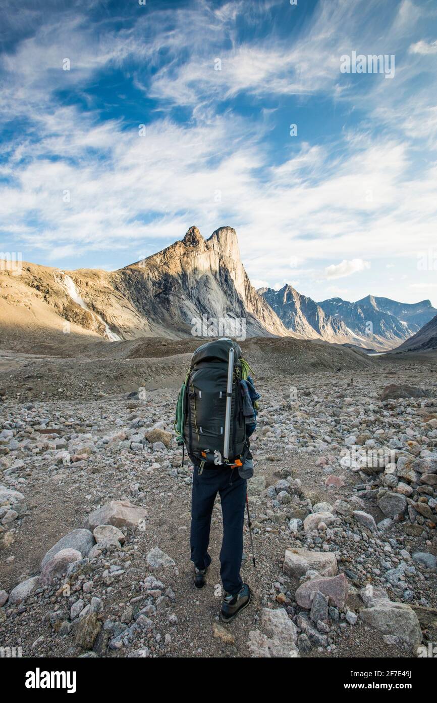 Rear view of climber looking at Mount Thor. Stock Photo