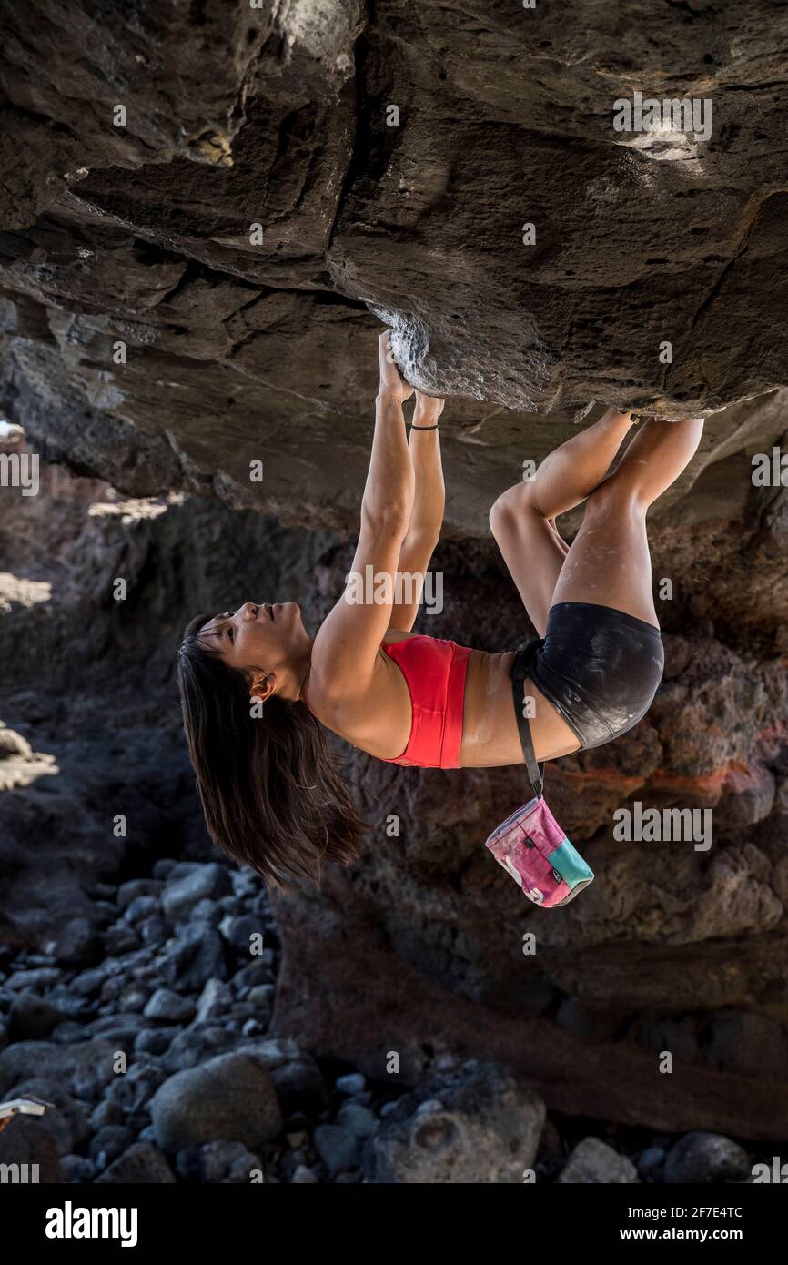 Young, fit asian woman climbing a rock upside down Stock Photo - Alamy