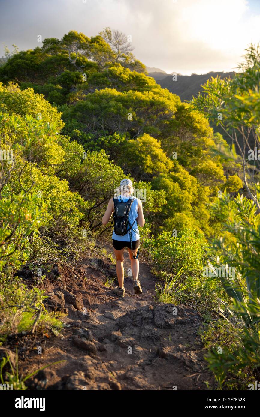 Adventurous blonde woman hiking down a rocky trail in Hawaii Stock Photo