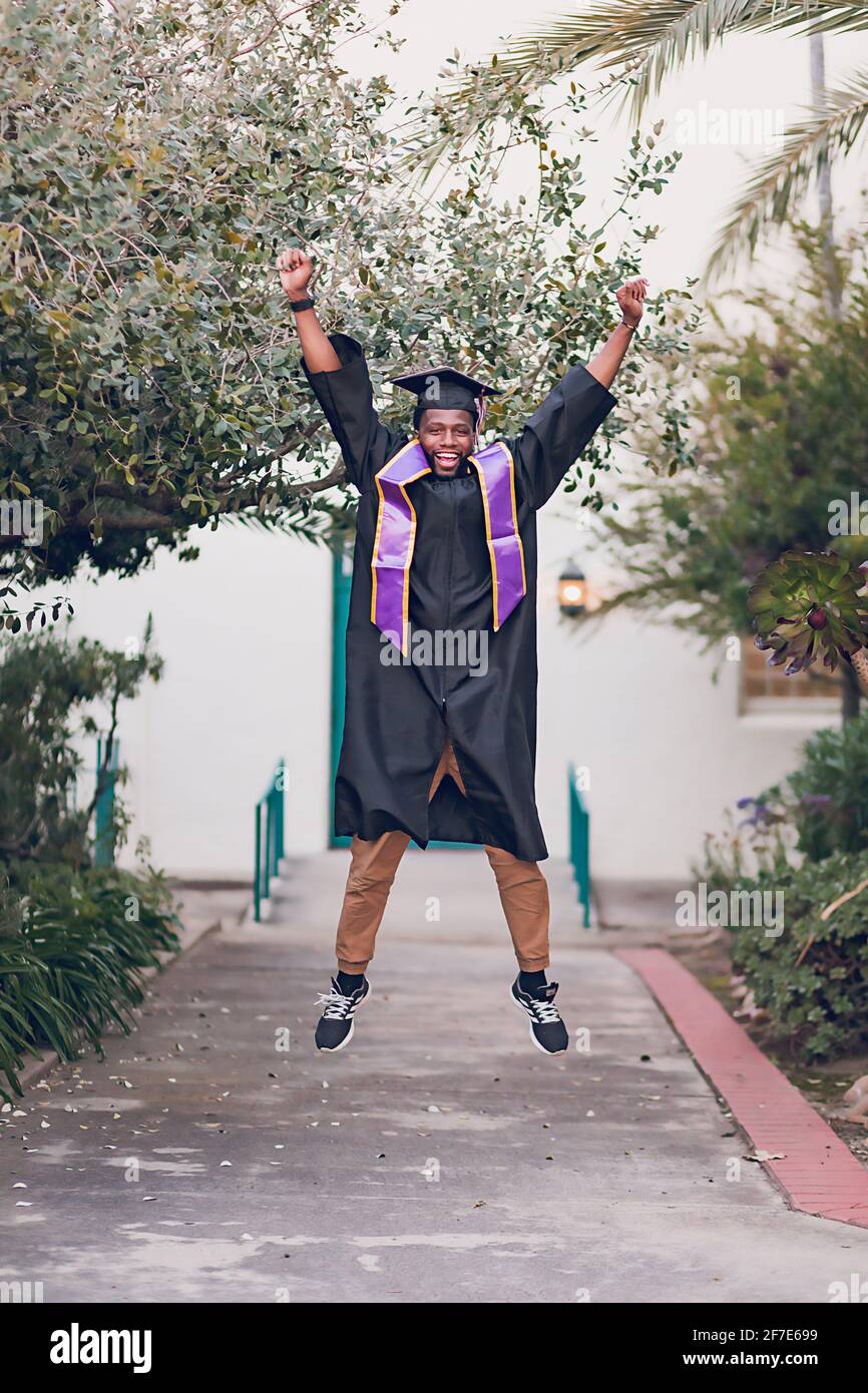 Man excited to be graduating college, wearing a graduation gown/cap. Stock Photo
