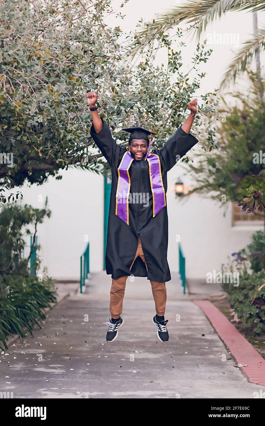 Man excited to be graduating college, wearing a graduation gown/cap. Stock Photo