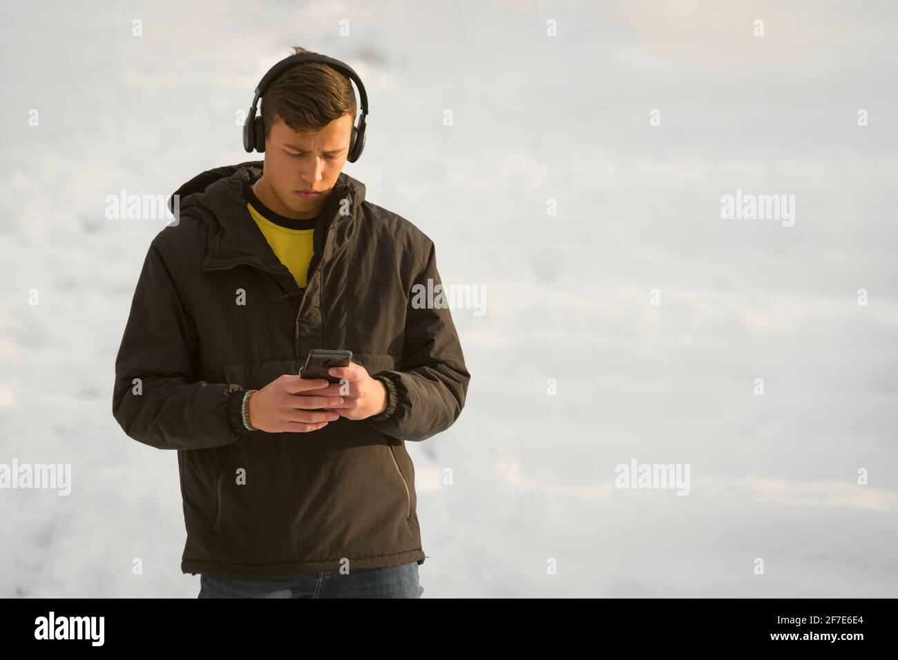 Blue-eyed millennial student boy listening music on headphones Stock Photo
