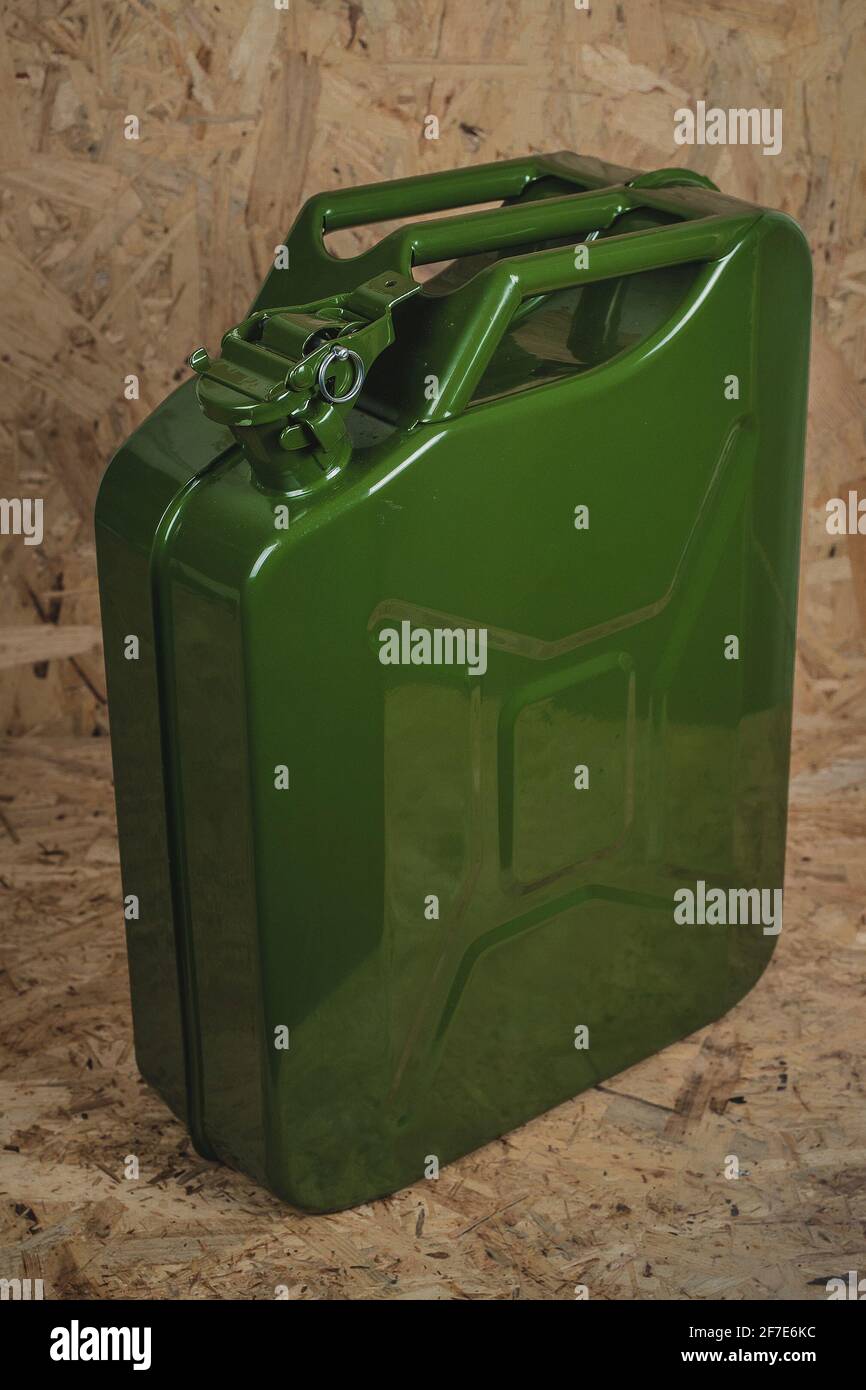 Brand new green metal jerry can or gas container standing on a wooden surface and background. Shiny jerry can in green color Stock Photo