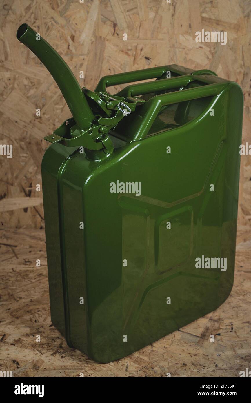 Brand new green metal jerry can or gas container standing on a wooden
