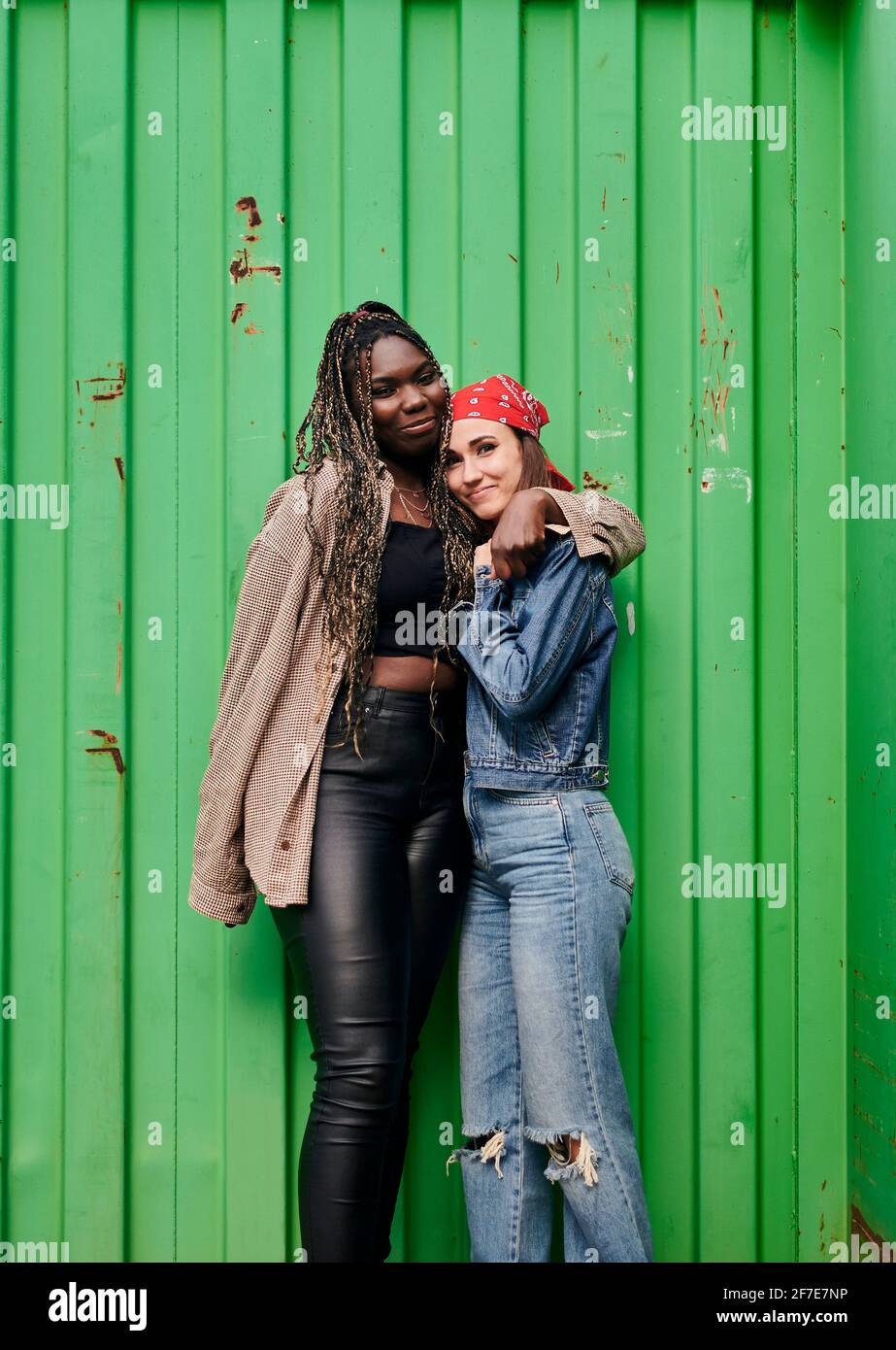 Two multi-ethnic women in urban clothing smile and hug each other Stock Photo