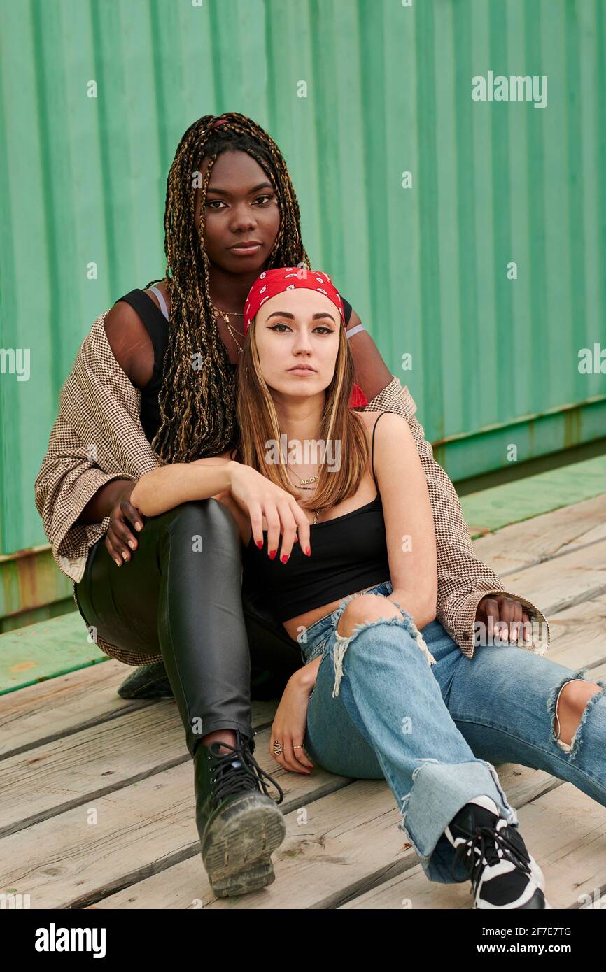 Multi-ethnic women embracing in urban clothing pose facing the camera Stock Photo