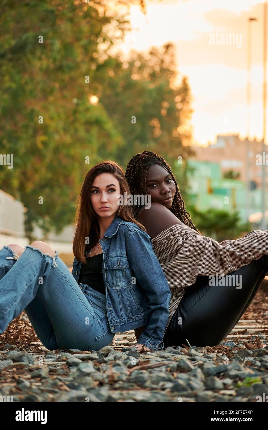 Two multi-ethnic young women pose and look at the camera at sunset Stock Photo