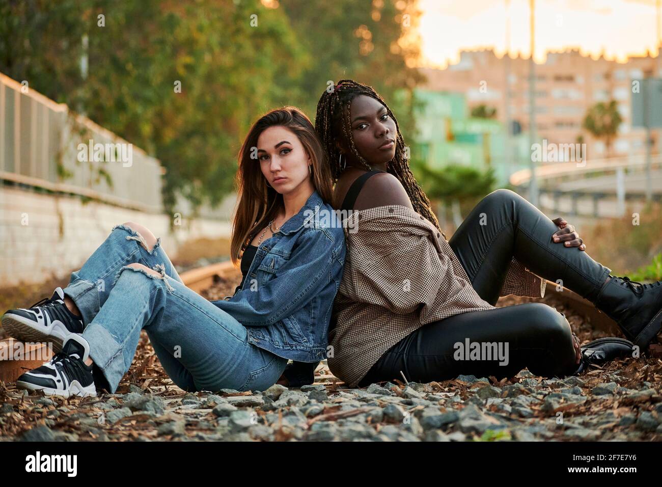Two multiethnic young women pose and look at the camera at sunset Stock Photo