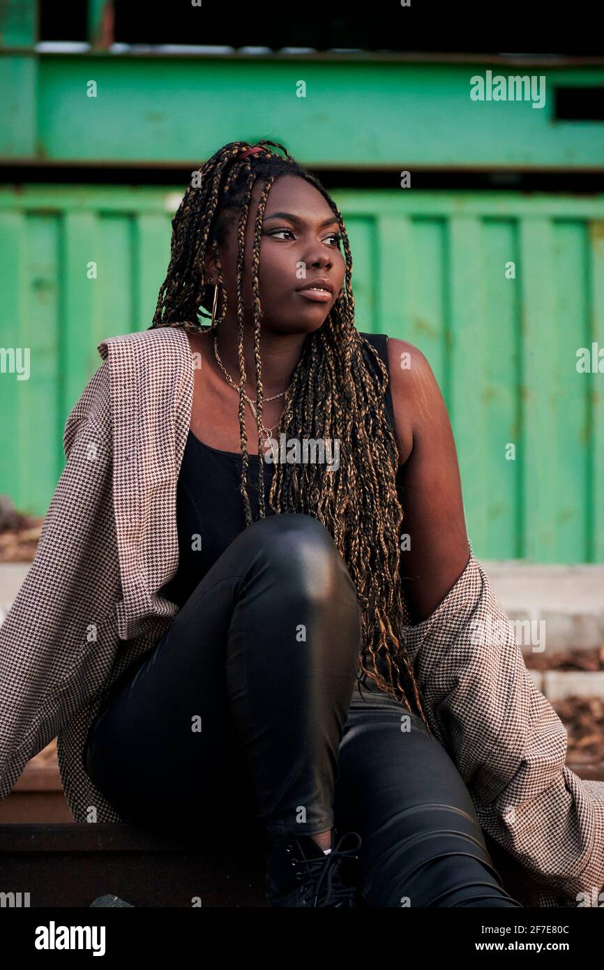 Black woman in urban clothing is sitting on abandoned train tracks Stock Photo