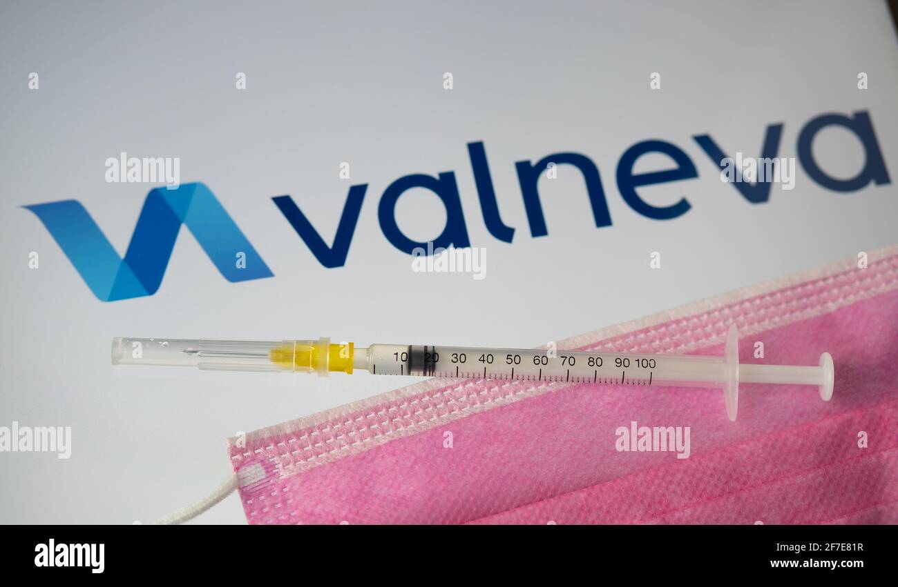 Valneva COVID-19 vaccine concept. Syringe, face mask and Valneva company logo on the blurred background screen. Stafford, United Kingdom, April 6, 202 Stock Photo