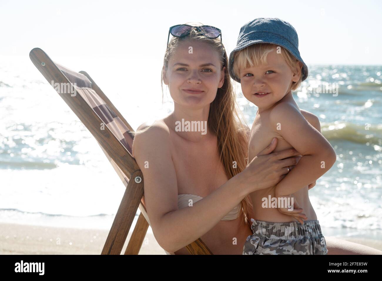 Family on the beach. Woman with child at sunrise sitting on a sun lounger, lifestyle Stock Photo
