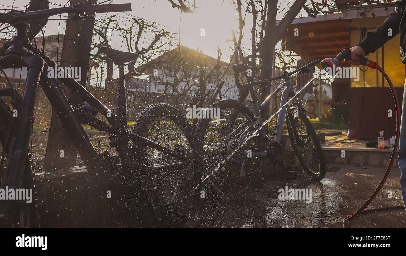 Person cleaning mountain bikes with the aid of a water jet. Panoramic