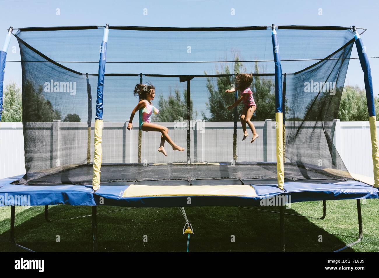 Sisters enjoying summer on the trampoline with a sprinkler Stock Photo