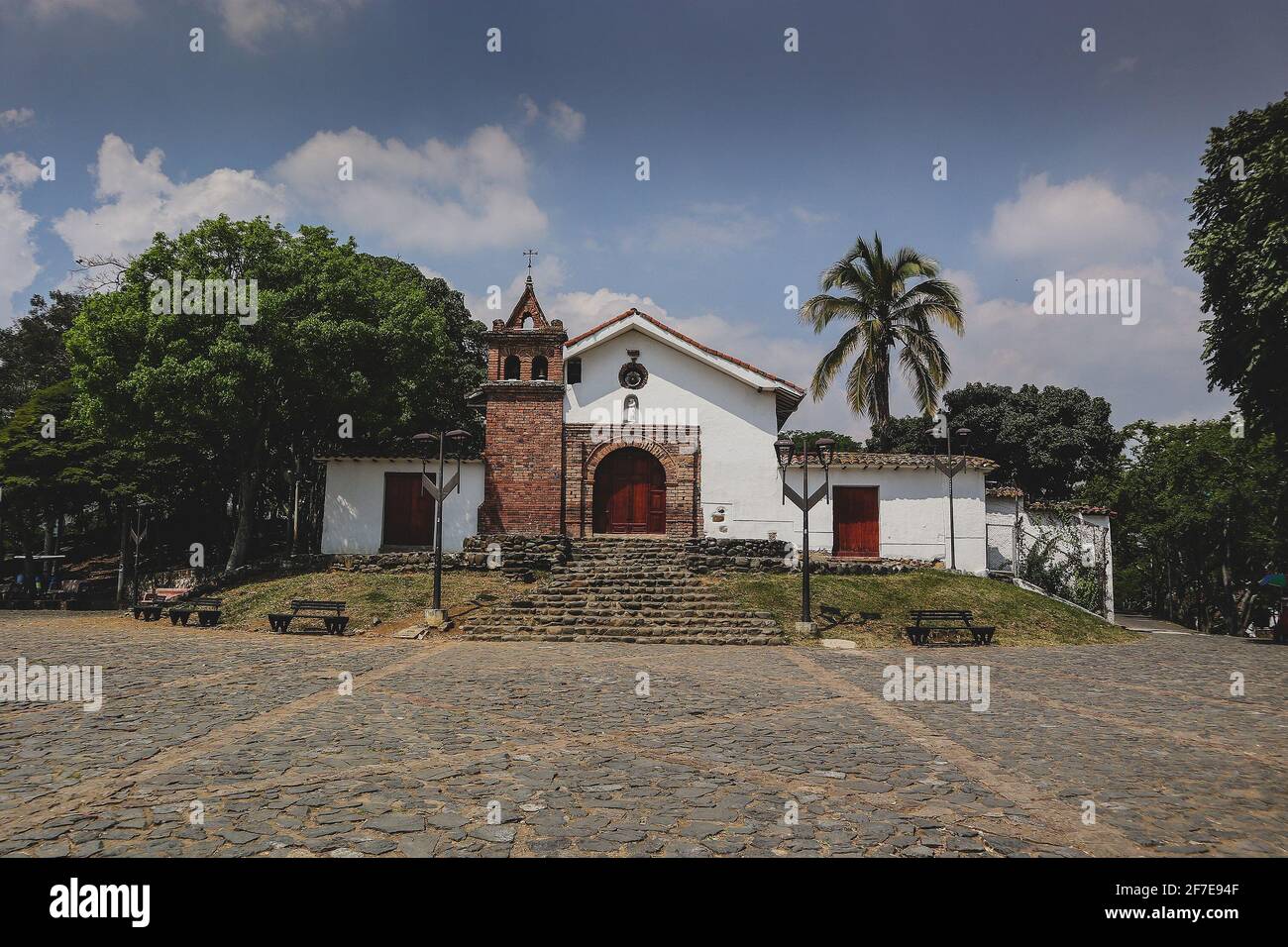 Church of San Antonio above the city of Cali, Colombia, on a sunny day with some clouds. Cobblestone road in front is visible. Stock Photo