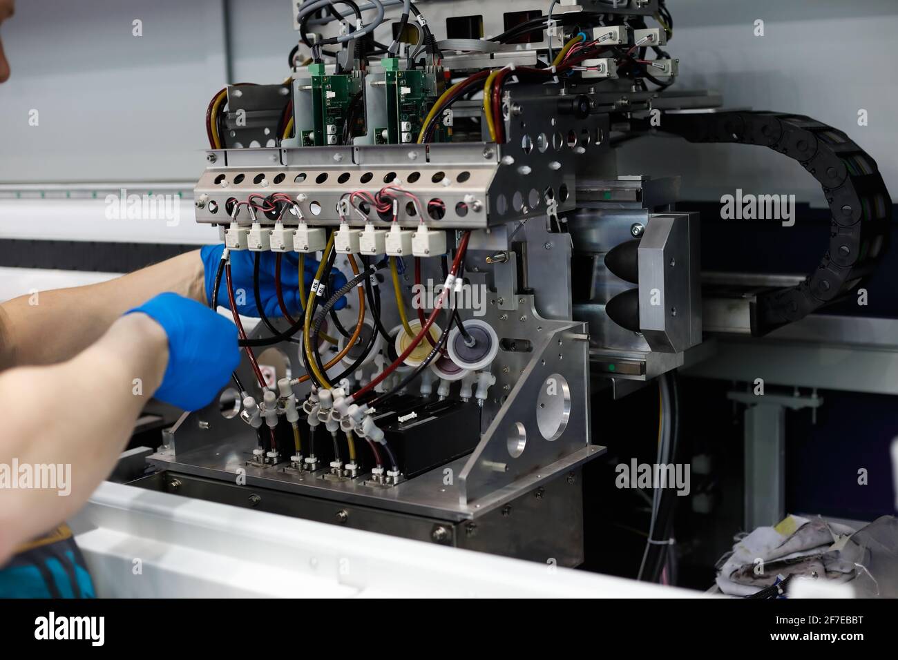 Male technician performs maintenance work on large format floor standing fabric printer. Stock Photo
