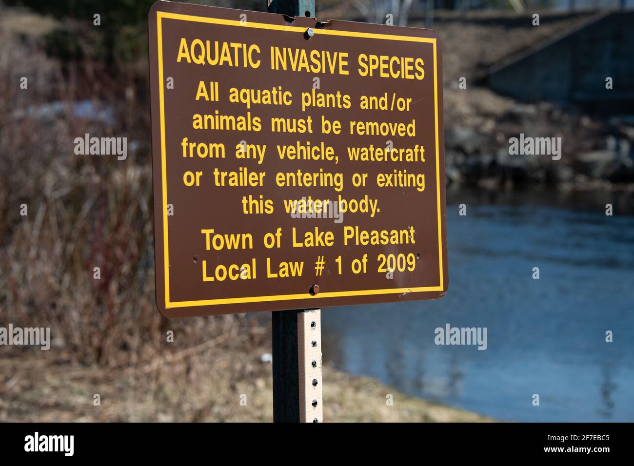 A sign on the Sacandaga River requiring aquatic plants and animals must be removed from vehicles, watercraft or trailers entering this water. Stock Photo