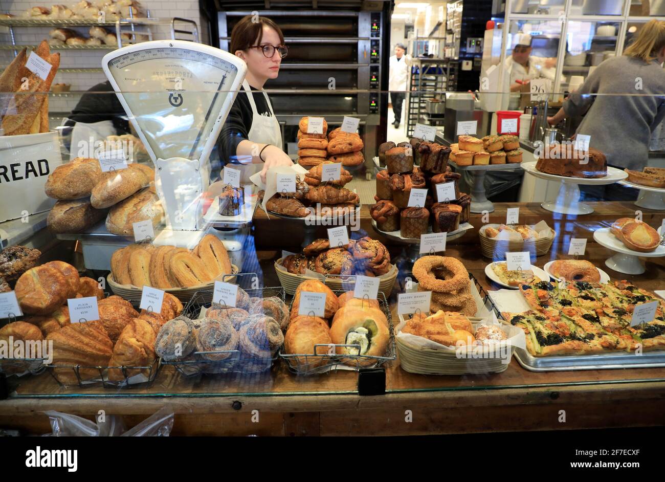 Baked goods for sale inside Tatte Bakery & Cafe with a female store