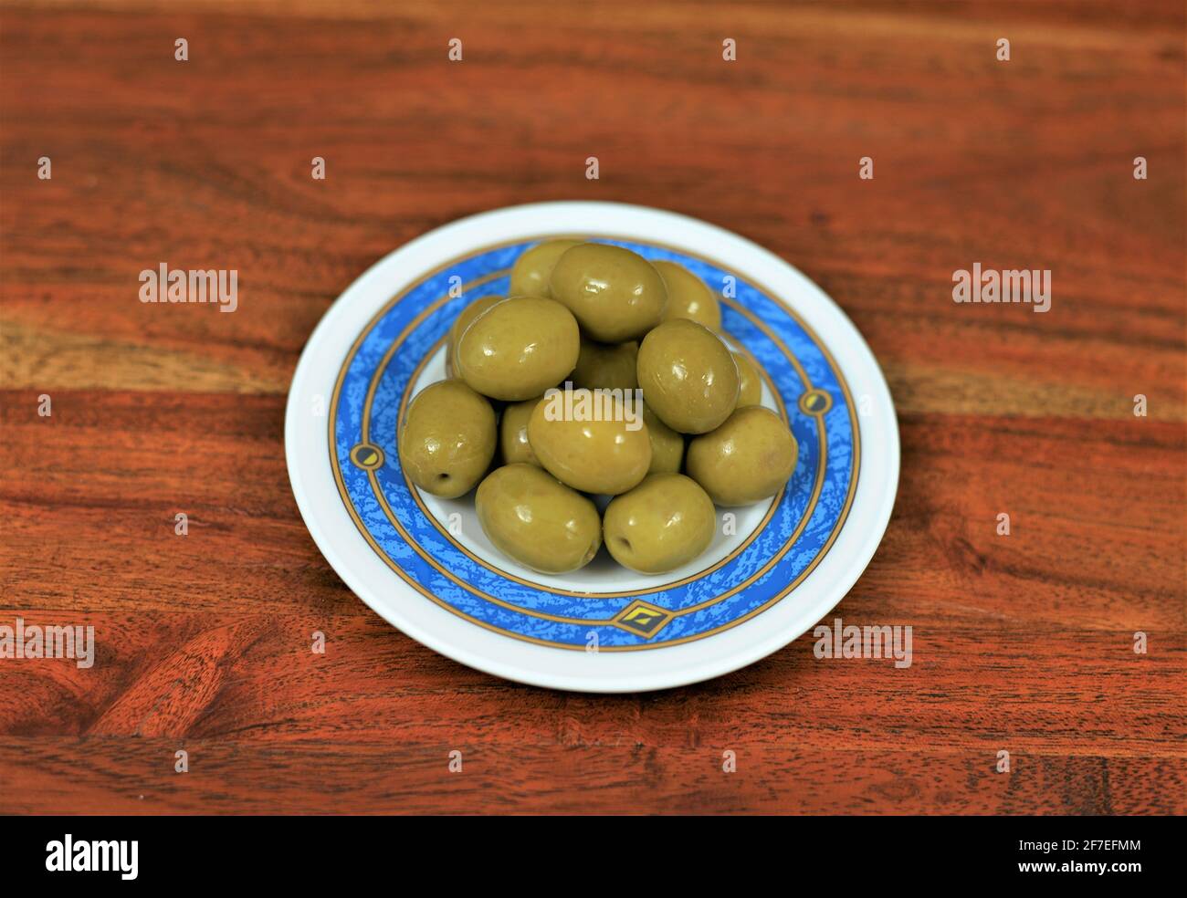 Andalucian green olives on a plate on a wooden table Stock Photo