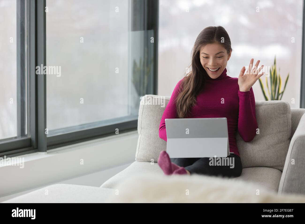 Working from home Asian woman on remote work online video meeting waving hello to her colleagues on webinar live stream videocall videoconference Stock Photo