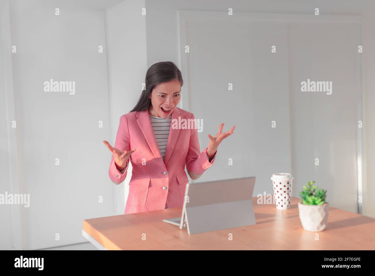 Angry business woman with bad internet connection working on laptop from home during videocall online with work colleagues. Asian businesswoman Stock Photo