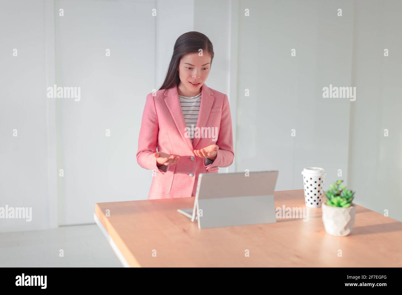 Videoconference online presentation Asian business woman talking teaching live webinar from home office streaming from laptop on standing desk Stock Photo