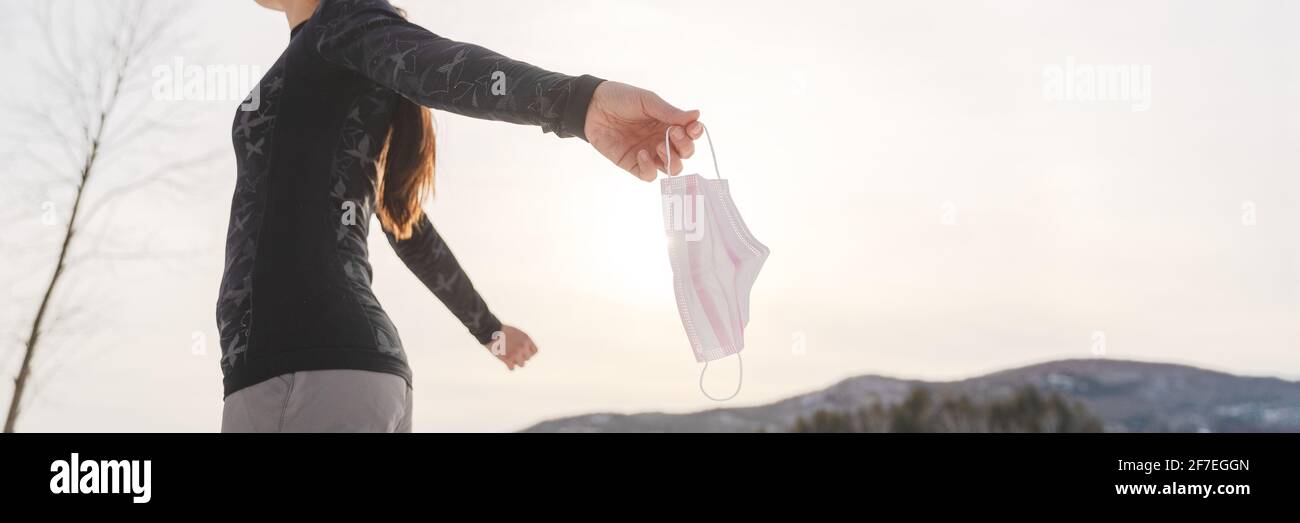 Coronavirus woman free of mask after pandemic end. Panoramic banner healthcare person holding medical face ppe mask letting go for freedom after Stock Photo