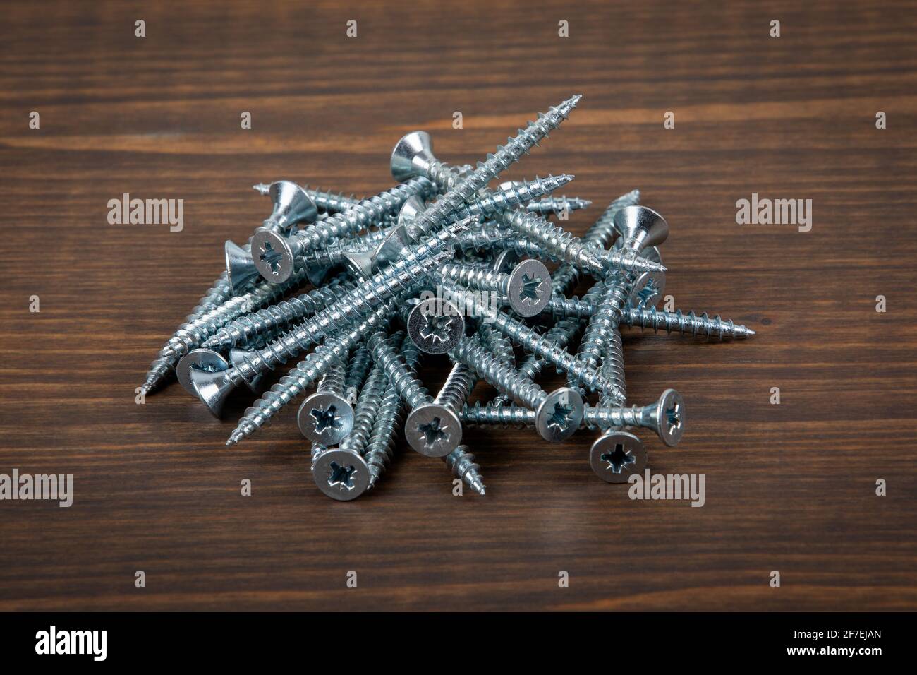 Metal screws in stack on a wooden background Stock Photo - Alamy