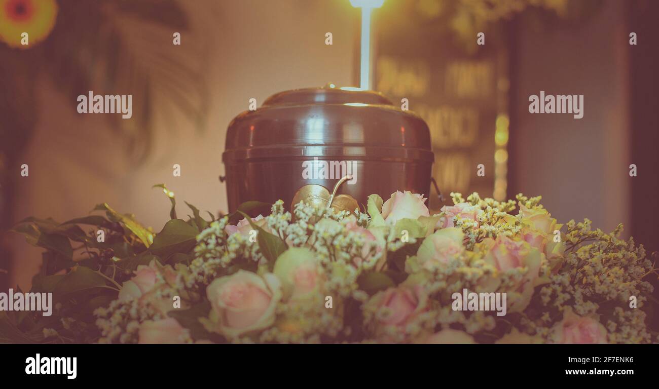 A metal urn with ashes of a dead person on a funeral with noone around on a memorial service. Sad grieving moment at the end of a life. Last farewell Stock Photo